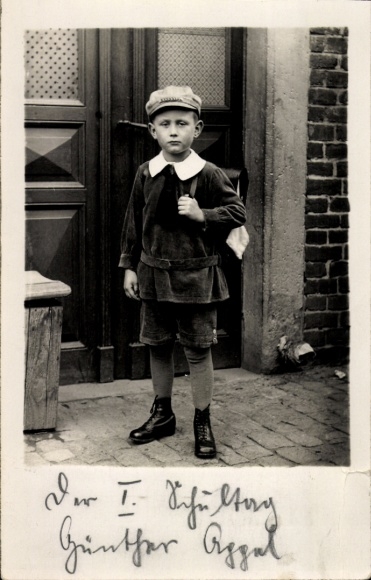 Postcard Dresden Bühlau, schoolboy with cap and satchel stands in front of a front door.