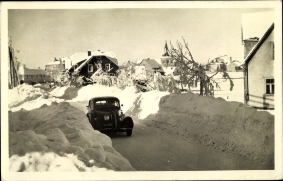 Postcard Neustadt in Sachsen, snow-covered street, wooden building, church tower, car in the snow