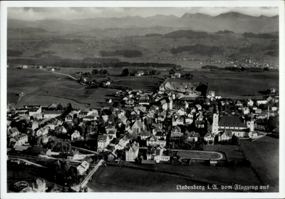 Ak Lindenberg im Allgäu Schwaben, luchtfoto van bergen op de achtergrond, kleine huisjes, kerk